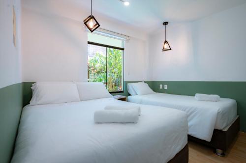 2 weiße Betten in einem Zimmer mit Fenster in der Unterkunft Casa Samaykuy in Ayacucho