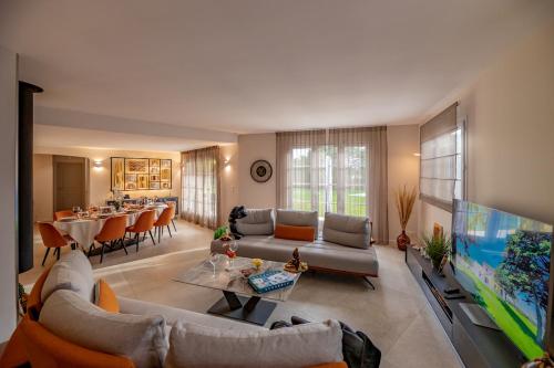 uma sala de estar com um sofá, uma televisão e uma mesa em Mas de Ceoulet - Villa de Luxe en Camargue em Arles