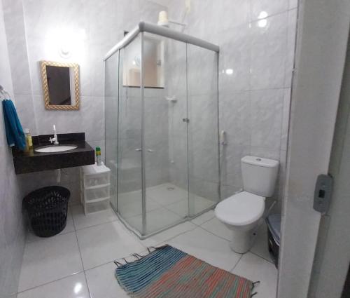 a bathroom with a shower and a toilet and a sink at Coroa Aconchego in Porto Seguro
