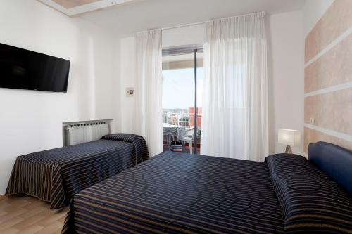 sypialnia z 2 łóżkami i telewizorem z płaskim ekranem w obiekcie Residenza Levante w mieście Riccione