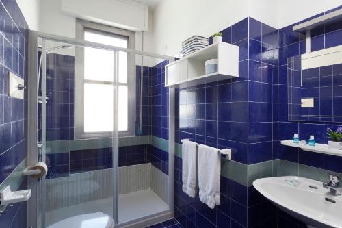 W wyłożonej niebieskimi kafelkami łazience znajduje się prysznic i umywalka. w obiekcie Residenza Levante w mieście Riccione