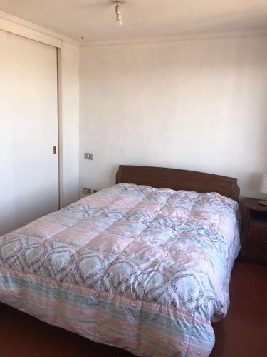 um quarto com uma cama com um edredão colorido em Arriendo Departamento em Santiago