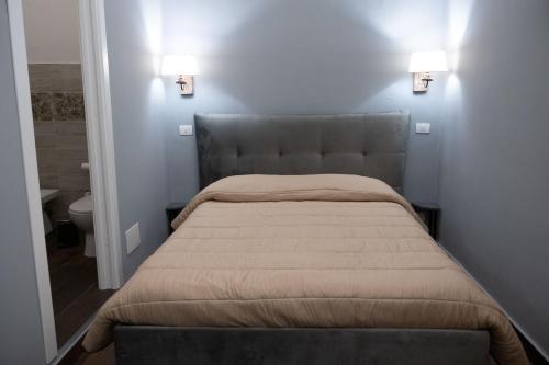 - un lit dans une chambre avec deux lumières sur le mur dans l'établissement B&B Palazzo Fischetti, à Catane