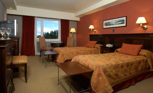 ein Hotelzimmer mit 2 Betten und einem Tisch in der Unterkunft Hotel Quijote in El Calafate