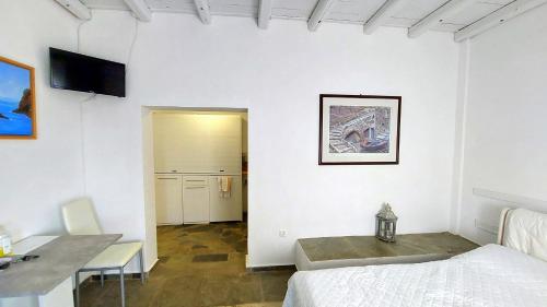 Cette chambre blanche comprend un lit, une table et un bureau. dans l'établissement Apollon-Artemis Apartments, à Apollonia