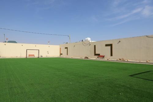 a building with a basketball hoop and a green field at شاليه أمي لولوة in Az Zulfi
