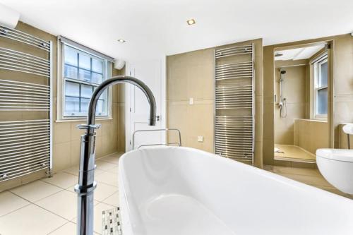 a bathroom with a tub and a toilet and a sink at Piccadilly House in London