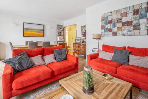 salon z 2 czerwonymi kanapami i stołem w obiekcie Spacious apartment with balcony in Paris - Welkeys w Paryżu