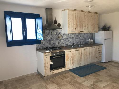 uma cozinha com armários de madeira, um lavatório e um frigorífico em Casa Caterina em Orosei
