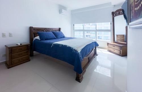 1 dormitorio con cama azul y espejo en Apartmento Edificio Porto Vento, en Cartagena de Indias