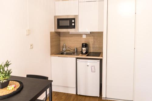 eine kleine Küche mit einer Spüle und einer Mikrowelle in der Unterkunft Charmant studio avec Parking privé - Proche Part-Dieu in Villeurbanne
