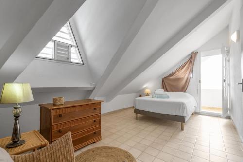 ein Schlafzimmer mit einem Bett, einer Kommode und einem Fenster in der Unterkunft Villa Rêve du Rocher in Le Diamant
