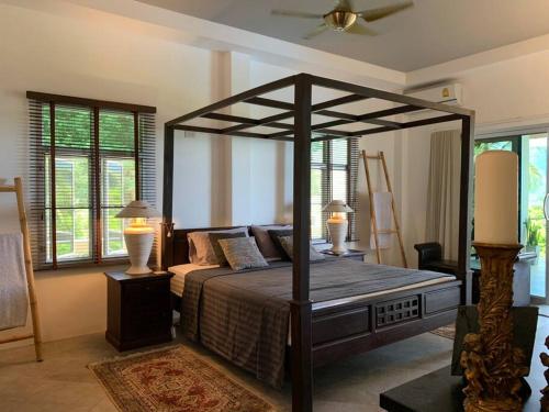 Maison d'exception في Nathon Bay: غرفة نوم بها سرير مظلة ومصباحين