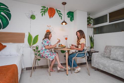two women sitting at a table in a room at FLORA New & beautiful studio apartment with rooftop in Cali