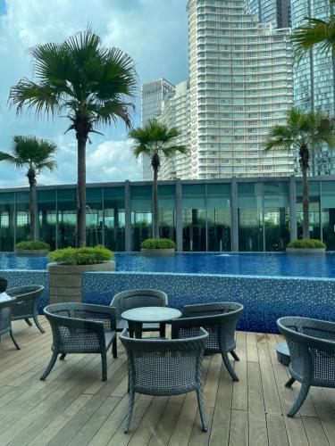 a swimming pool with tables and chairs and palm trees at Vortex Suites KLCC By Paradise IN Kuallampur City in Kuala Lumpur