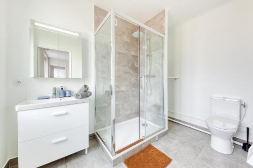 a white bathroom with a shower and a toilet at Cozy Appart 5 à 3' de la gare - Cozy Houses in Palaiseau