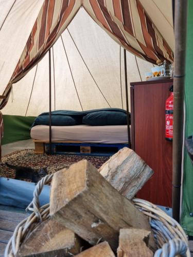 a bed in a tent with a basket of wood at Kampeerbeleving Dijksehoeve in Nistelrode