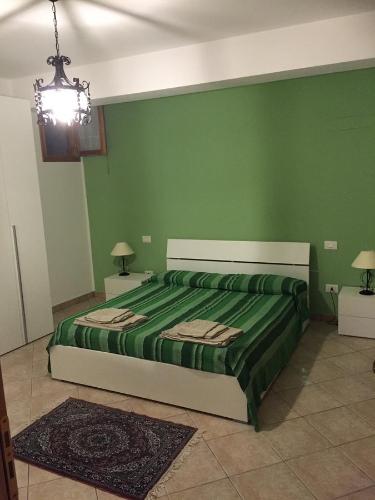 a bedroom with a bed with green walls and a chandelier at Dall'Orso Grigio in Balestrate