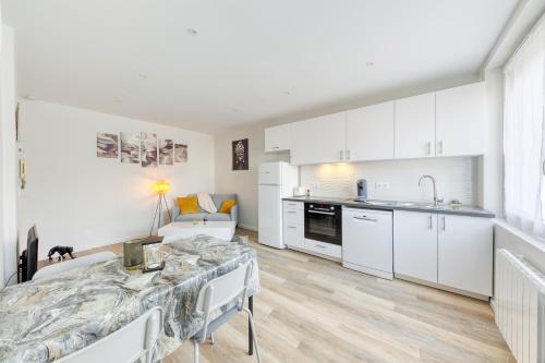 a kitchen and living room with white cabinets and a table at Cozy Appart 5 à 3' de la gare - Cozy Houses in Palaiseau