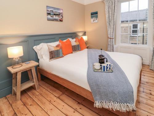 a bedroom with a bed with orange pillows at The Cobbles in Alnwick
