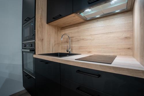 une cuisine avec un évier et une cuisinière dans l'établissement Le Saint-André - Clim - Loft romantique avec Jacuzzi - BY PRIMO C0NCIERGERIE, à Buxy