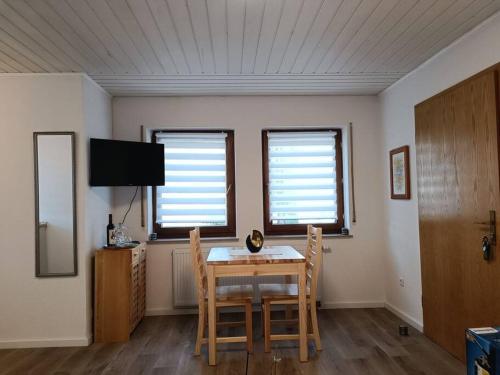 a dining room with a table and chairs and two windows at Ferienwohnung in Oberrot in Oberrot