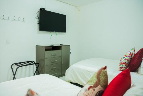 a bedroom with two beds and a tv on the wall at Hotel Bungalows Casa Blanca in Tenancingo de Degollado