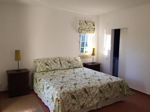 a bedroom with a bed and two night stands and a window at Casa das Xaras in Sintra