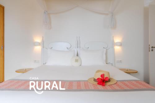 a hat with a red flower sitting on top of a bed at Casas Da Vereda in Estreito da Calheta