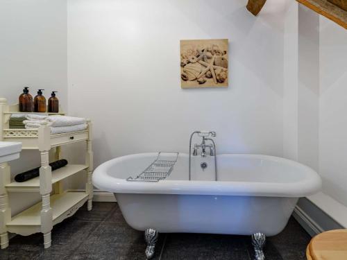 6 bed in Barnstaple 85615 في Tawstock: حوض استحمام أبيض في حمام مع رف