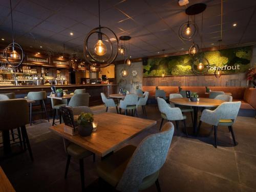 a restaurant with tables and chairs and a bar at Chalet by Pond with Sauna in Veldhoven