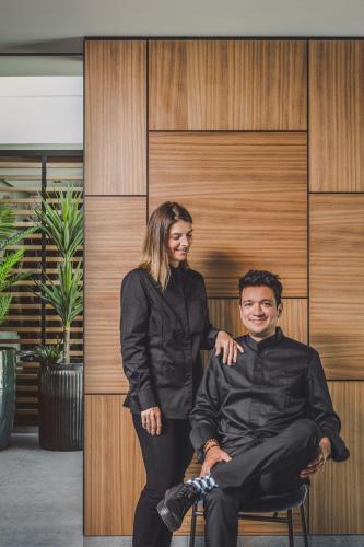 a woman standing next to a man sitting on a chair at 3 VIE Restaurant & Rooms in Acquarossa