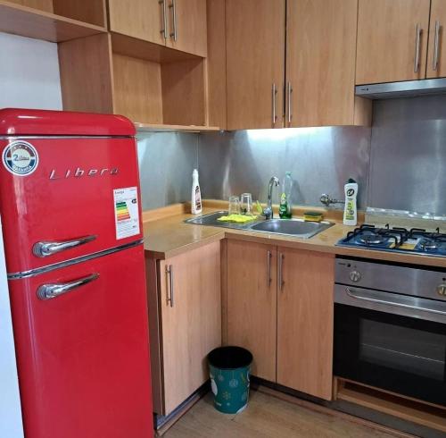 um frigorífico vermelho numa cozinha com um lavatório em Apart Hotel AR em Santiago