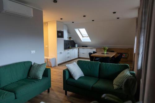 APartament Piaskowa في جنيفينو: غرفة معيشة بها كنبتين خضراء وطاولة