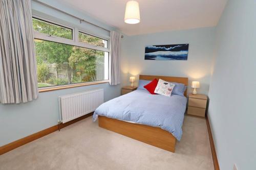 een slaapkamer met een bed en een groot raam bij Luxury Detached Home Close to Strangford Lough in Killinchy