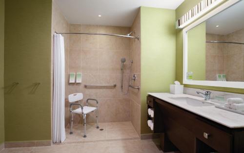 a bathroom with a shower and a sink and a chair at Home2 Suites By Hilton Winter Garden in Orlando