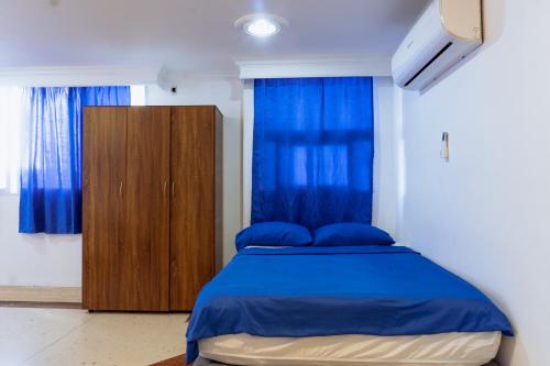 een slaapkamer met een blauw bed en een houten kast bij Acogedor Loft Laguito 1 Habitacion N in Cartagena