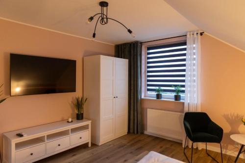 a living room with a tv and a cabinet and a window at APartament Piaskowa in Gniewino