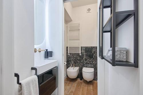 een badkamer met een wastafel, een toilet en een spiegel bij [Moderno Bilocale Chic] 8 min dal Duomo in Milaan