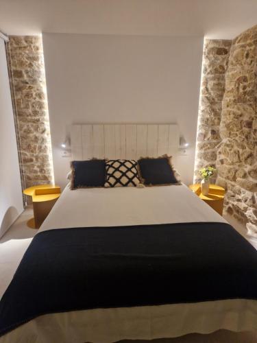 a bedroom with a large bed and two stone walls at A casa d'abaixo in Parada del Sil