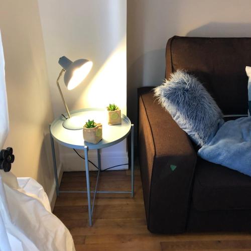 une table de chevet avec une lampe et un canapé dans l'établissement #M3 Irvoy's mystery Cours Jean Jaurès Tramway, à Grenoble