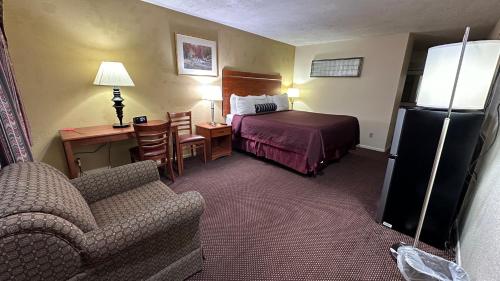 una camera d'albergo con letto, scrivania e divano di Economy Inn a Garnett