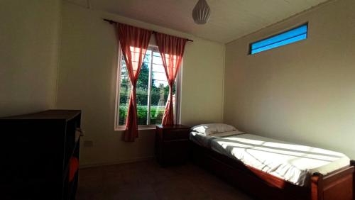 a bedroom with a bed and a window with red curtains at Balcones de playa de oro in Villa Independencia