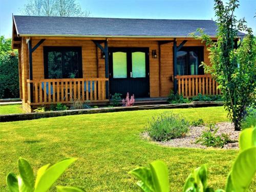 a wooden cabin with a lawn in front of it at The Malvern Hills, Courtyard Cabins, Barbara Cabin in Great Malvern