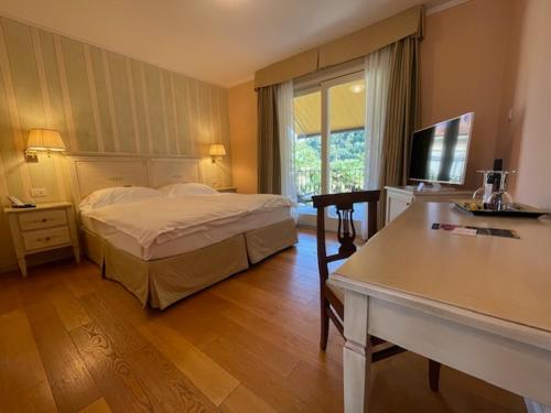 a bedroom with a bed and a table and a television at Villa Palmira Kinderfreies Hotel in Cannobio