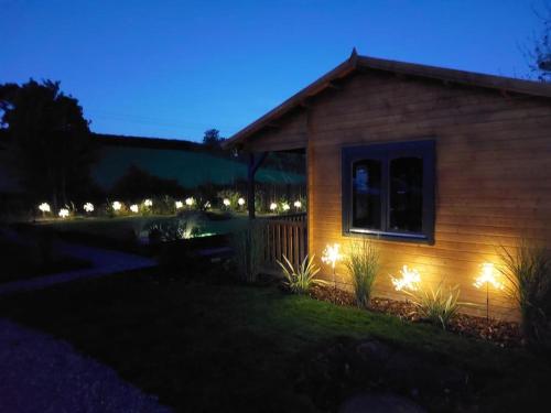 a house with lights on the side of it at night at The Malvern Hills, Courtyard Cabins, Barbara Cabin in Great Malvern
