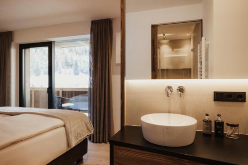a bathroom with a sink and a bed and a mirror at Luxury Chalet Milé in Ortisei