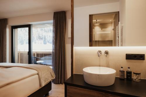 a bathroom with a sink and a bed and a mirror at Chalet Milé in Ortisei