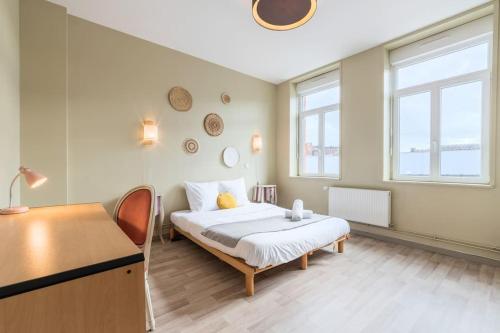 een slaapkamer met een bed, een bureau en 2 ramen bij Grande Maison de Maître - Élégante avec Terrasse in Roubaix