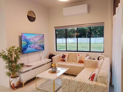 sala de estar con muebles blancos y ventana grande en Beach Hive Seafront Residences Villa in San Juan Batangas, en Batangas